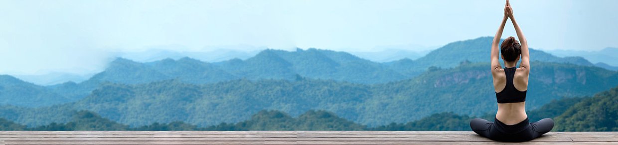 Frau in Yoga-Pose vor Berglandschaft – Symbolbild für Achtsamkeit und Balance im weiblichen Zyklus